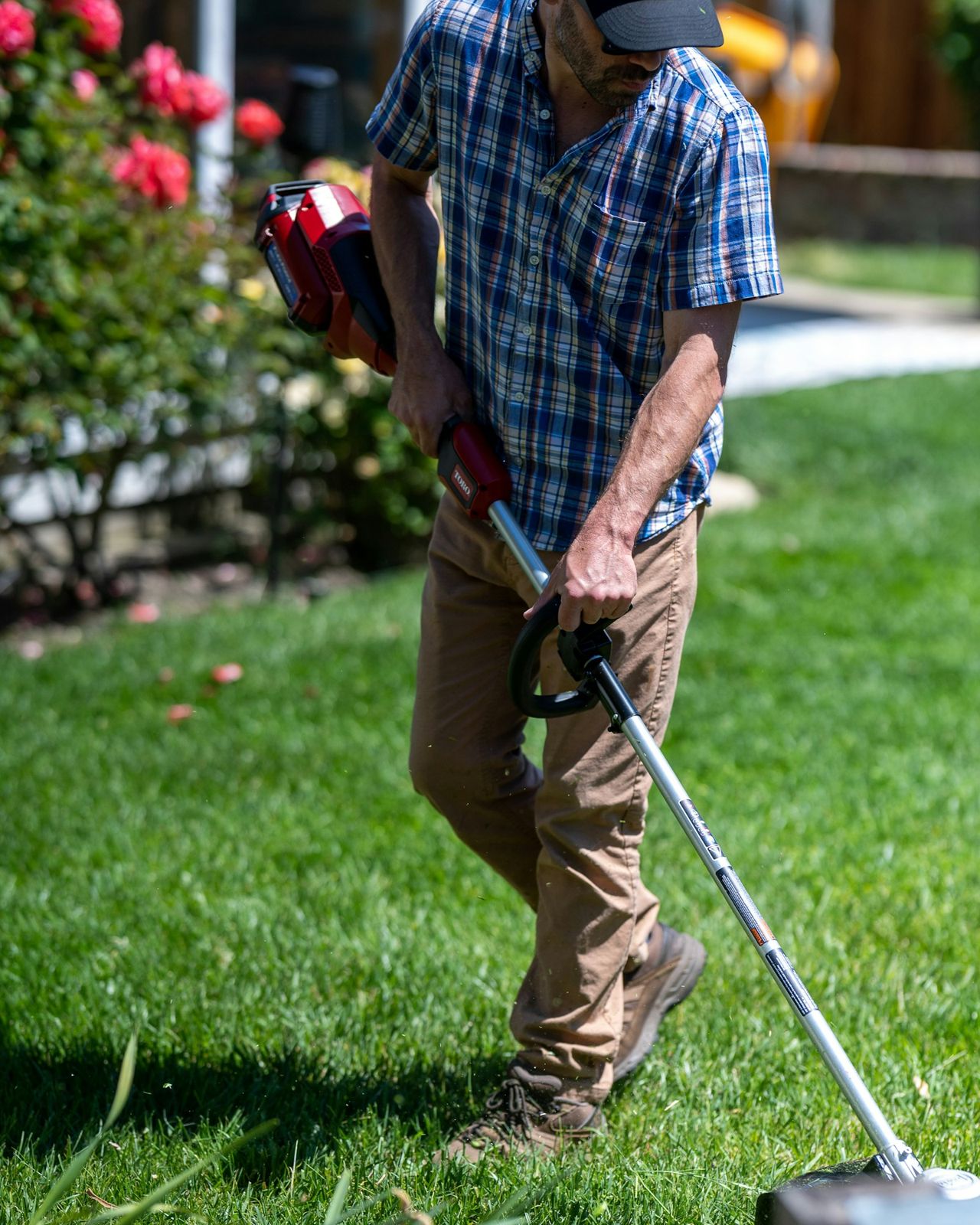 Landscaper string-trimming the edge of a lawn